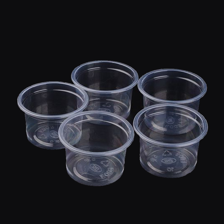 Os copos plásticos Jello da parcela das tampas dispararam em copos para provar o petisco do molho